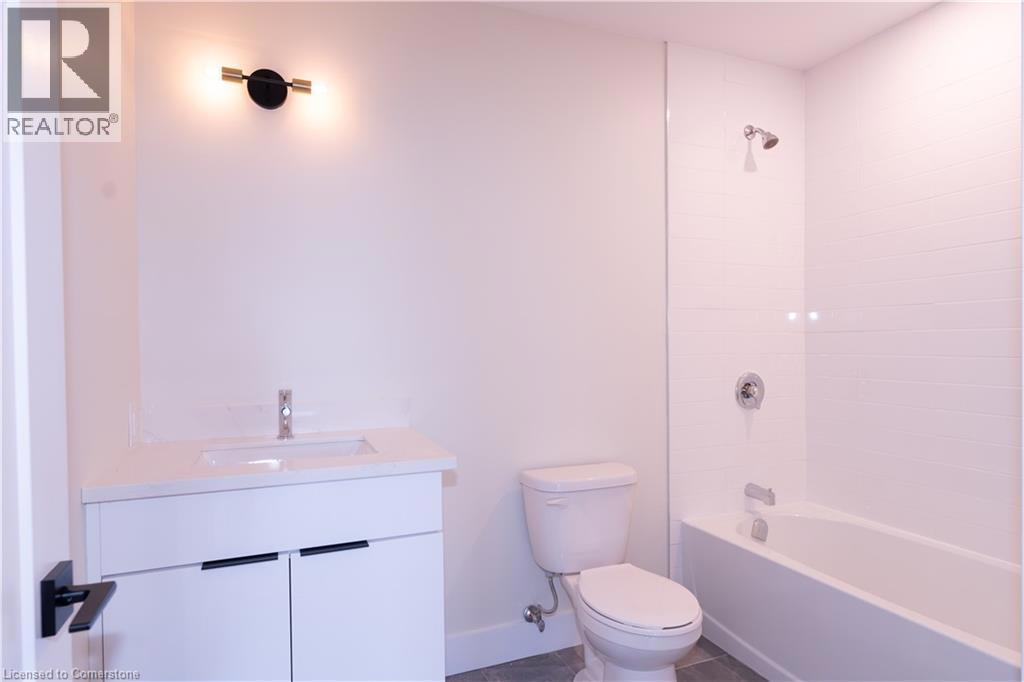 169 JAMES Street S Unit# 601=Bathroom featuring vanity, washtub / shower combination, and dark tile patterned floors