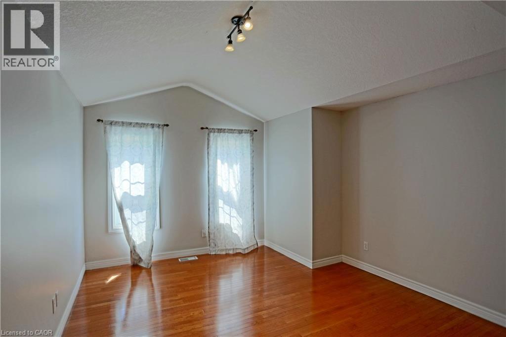 Unfurnished room with lofted ceiling, light wood finished floors, and a textured ceiling